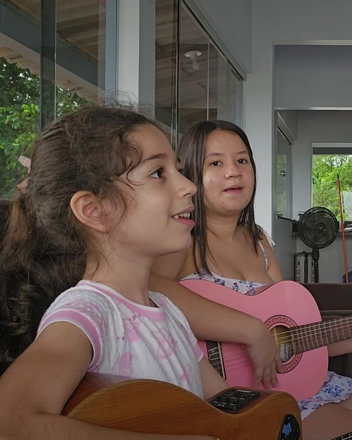Duas alunas pequenas com violões durante a aula