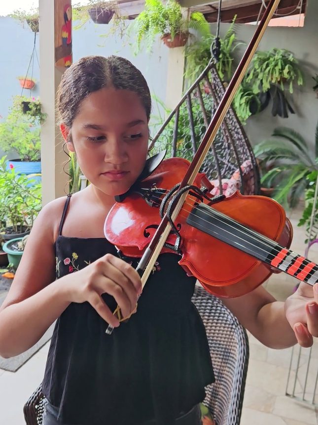 Aluna tocando um violino vermelho