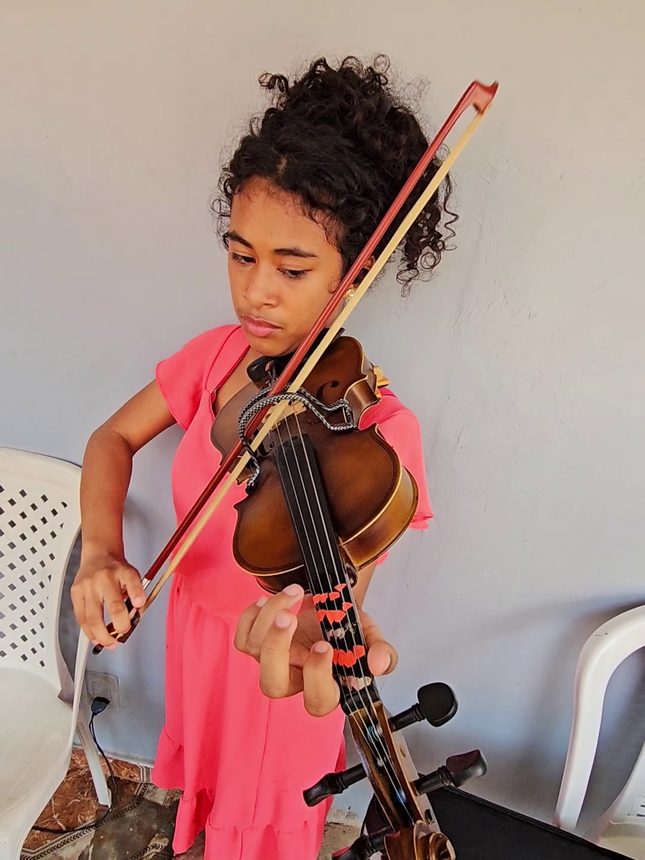 Aluna de vestido rosa tocando violino